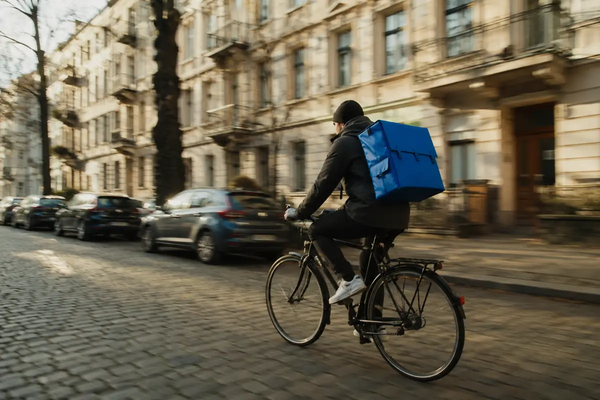 Fahrradkurier mit blauer Kuriertasche auf einer Berliner Straße